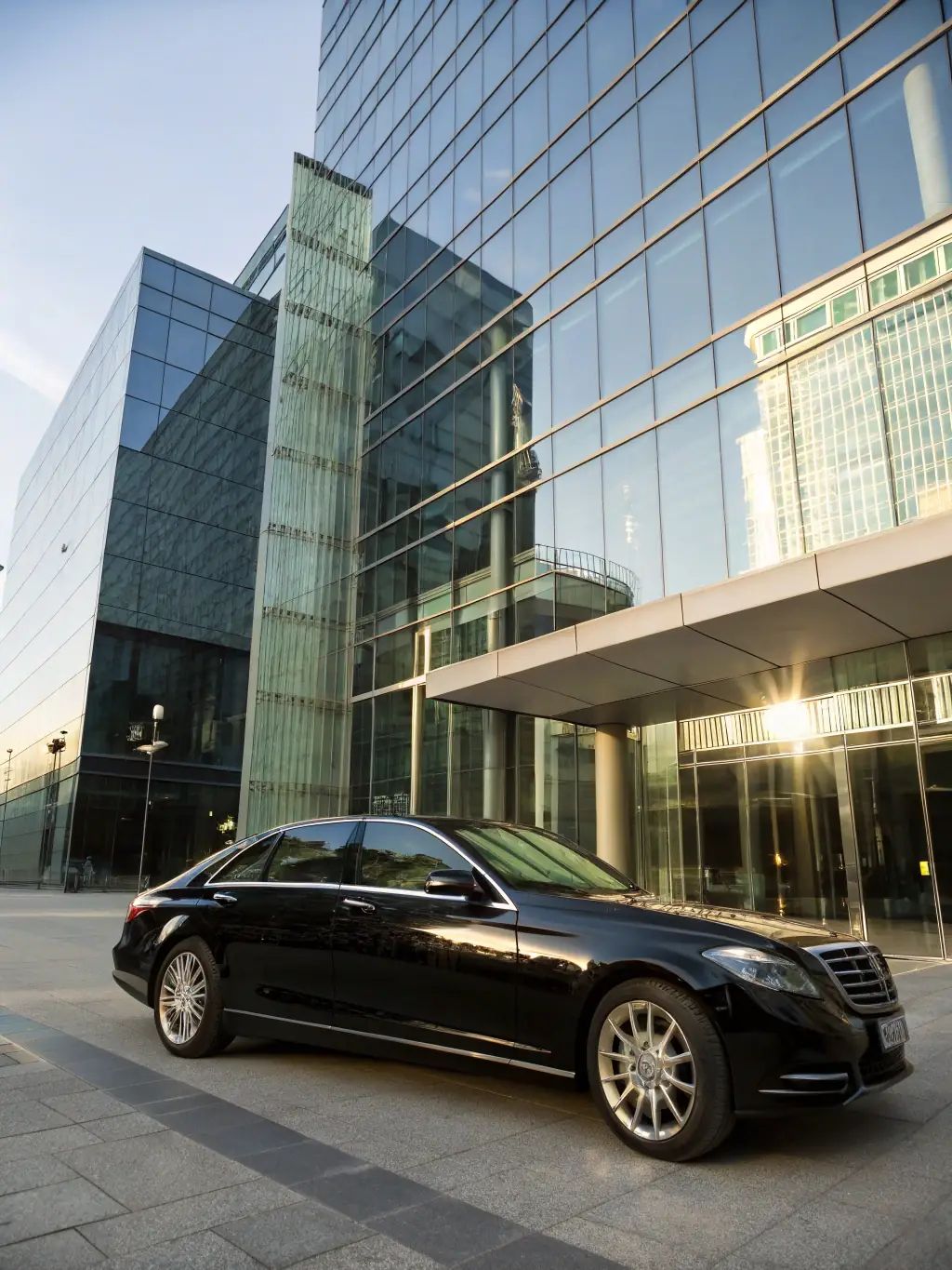 A sleek, black Mercedes-Benz S-Class parked in front of a modern office building, symbolizing corporate travel and executive transport for EliteDrive.